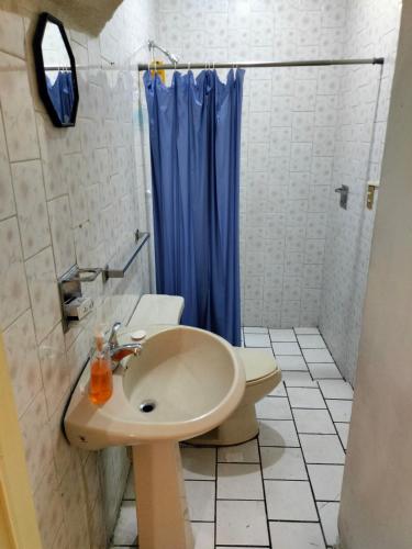 a bathroom with a sink and a blue shower curtain at Casa Lili in Cuernavaca