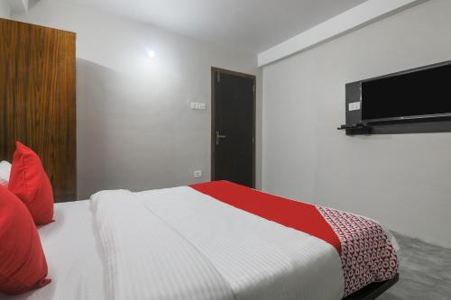 a bedroom with a bed and a television on the wall at Hotel O Pillars House in Shillong