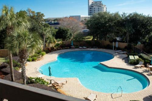 an overhead view of a swimming pool with chairs and trees at stylish luxe condo! in Fort Walton Beach