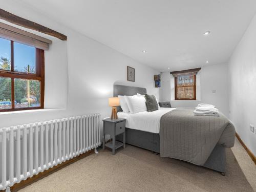 a white bedroom with a bed and a window at Swallow Barn in Cockermouth
