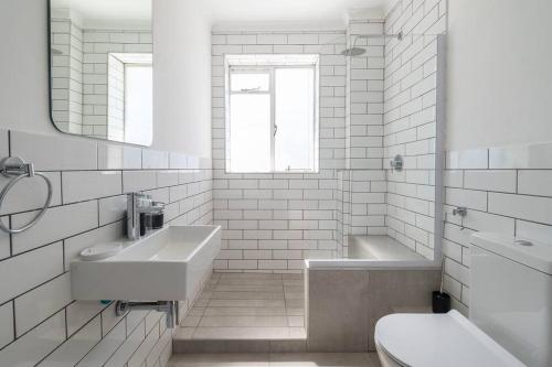 biała łazienka z umywalką, wanną i toaletą w obiekcie Claremont Apartment With Three Bedrooms w Kapsztadzie