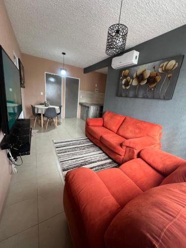 a living room with a red couch and a table at DEPARTAMENTO PASEOS DE XCACEL in Playa del Carmen