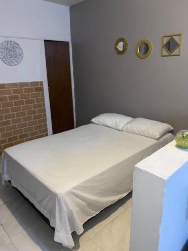 a white bed in a room with a brick wall at Cuarto privado con entrada independiente cerca al Poblado in Medellín