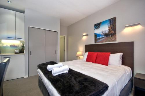 a bedroom with a large bed with red and white pillows at Pure Retreat Lake View in Queenstown