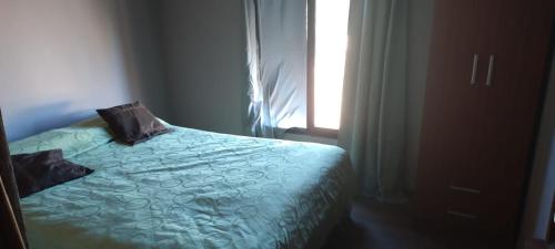 a bed with two pillows on it next to a window at casa necochea in Necochea