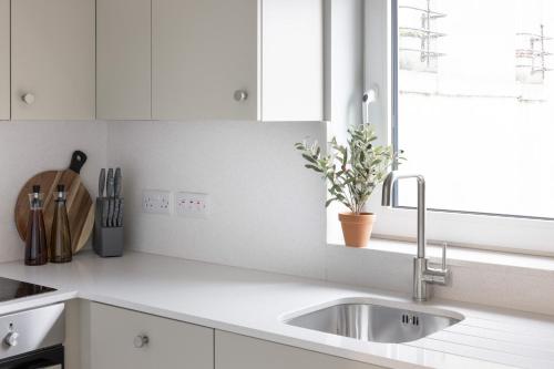 a white kitchen with a sink and a window at Urban Rest Merrion Square Apartments in Dublin