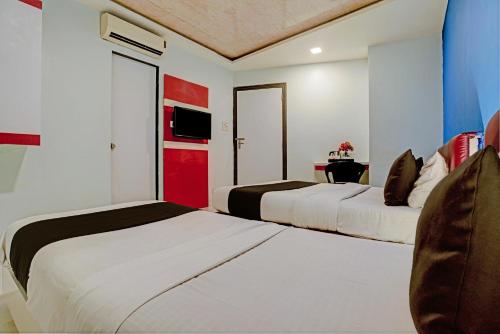 two beds in a hotel room with red and white at OYO Hotel Blue Sea Near Chhatrapati Shivaji International Airport in Mumbai