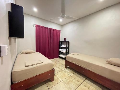 two beds in a room with a red curtain at Casa Bella Vista in Quepos