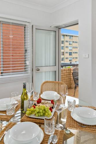 a table with a plate of grapes and wine glasses at Sea Vista Escape - A Charming Waterside Stay in Wollongong