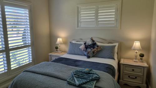 um quarto com uma cama com lençóis azuis e uma janela em Little Britton em Wingham