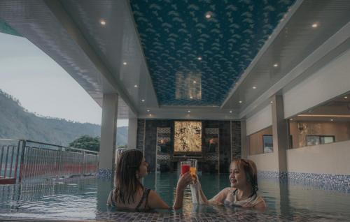 two girls are sitting in the water in a swimming pool at Agape Hotel Haranggaol in Haranggaul