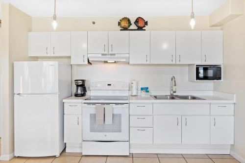 a white kitchen with white cabinets and appliances at Cozy & City View Steps to Waikiki Beach with Parking in Honolulu