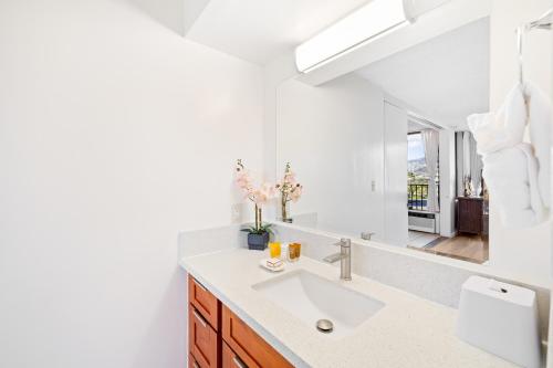 a white bathroom with a sink and a mirror at Cozy Waikiki Getaway, Stroll to Beach with Free Parking in Honolulu