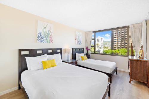 two beds in a hotel room with a window at Cozy & City View Steps to Waikiki Beach with Parking in Honolulu