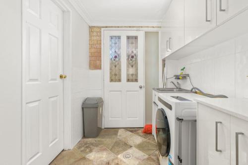 a white laundry room with a washer and dryer at Callala Beach Walk - Beachfront with Fireplace in Callala Beach
