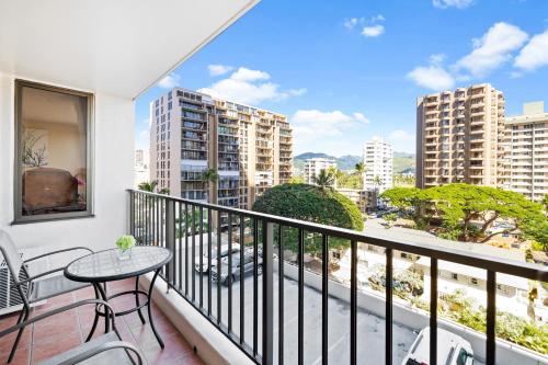 a balcony with a table and chairs and buildings at Cozy & City View Steps to Waikiki Beach with Parking in Honolulu