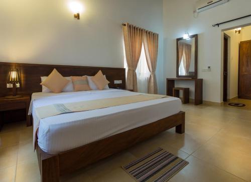 1 dormitorio con 1 cama grande y espejo en Hotel Chenra, en Kataragama