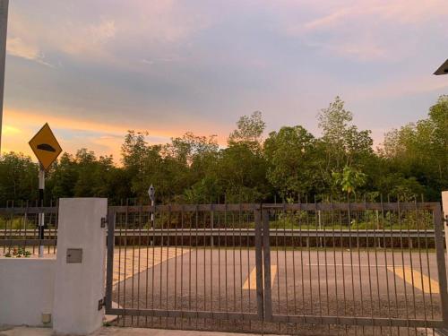a fence with a gate with a yellow sign on it at Juwita&Arjuna Homestay Teluk Senangin in Kampong Batu Tiga