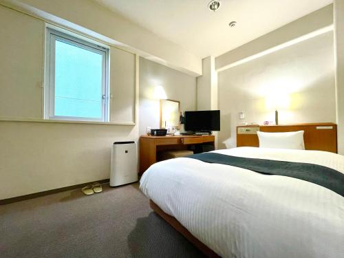 Aomori Green Park Hotel في أوموري: غرفة نوم بسرير ومكتب ونافذة