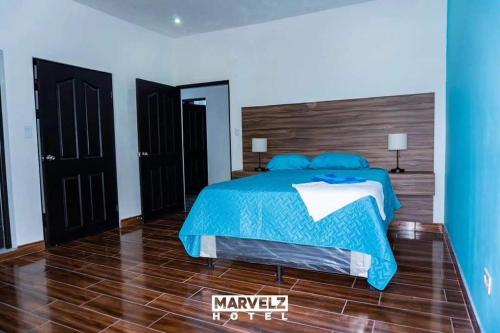 um quarto com uma cama com um edredão azul em Marvelz Hotel 