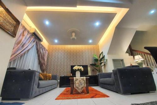 uma sala de estar com dois sofás e uma mesa em HANI MAWADDAH HOMESTAY SEKSYEN 7 SHAH ALAM em Shah Alam