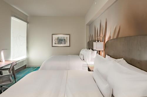 two white beds in a room with a desk at Element Dallas Downtown East in Dallas