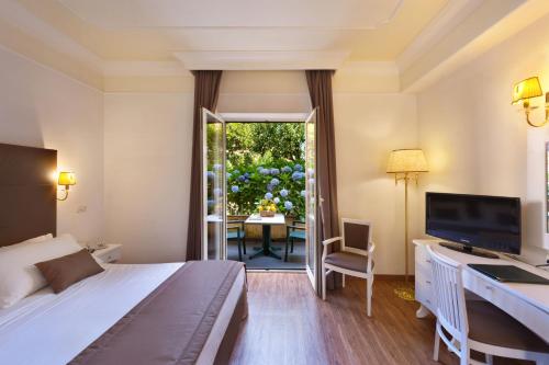 Habitación de hotel con cama, escritorio y TV. en Grand Hotel Parco del Sole - All Inclusive, en Sorrento
