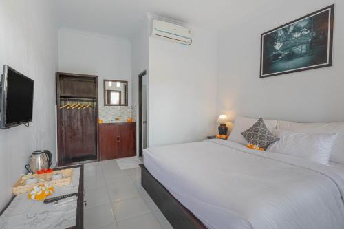 a bedroom with a large white bed and a television at Sekar Bali Homestay in Gianyar