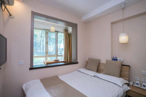 a bedroom with a bed and a large window at Harbin Hash International Youth Hostel Harbin West Station in Harbin