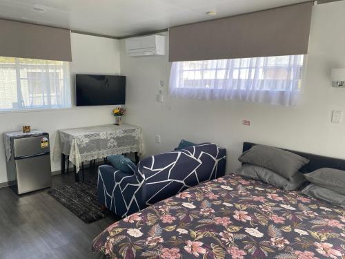 a bedroom with a bed and a table and a television at Self Contained En-Suite Private Bathroom, Private Entrance, Close to Shops & Hospital Homestay in Hamilton