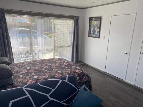 a bedroom with a bed and a large window at Self Contained En-Suite Private Bathroom, Private Entrance, Close to Shops & Hospital Homestay in Hamilton