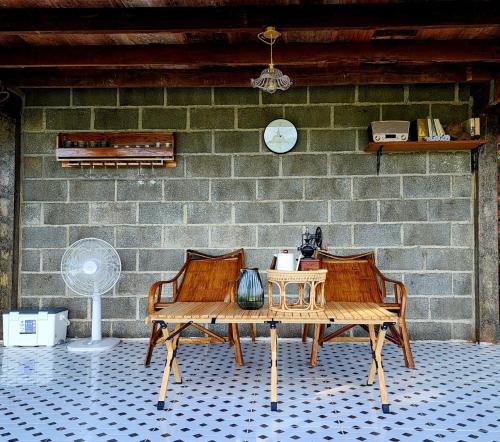a table and two chairs in front of a brick wall at บ้านเล็กในป่าใหญ่ at น่าน Little House In the Forest at Nan 