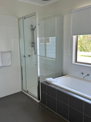 Portarlington Beach Motel في بورترلينجتون: حمام مع حوض استحمام ودش زجاجي