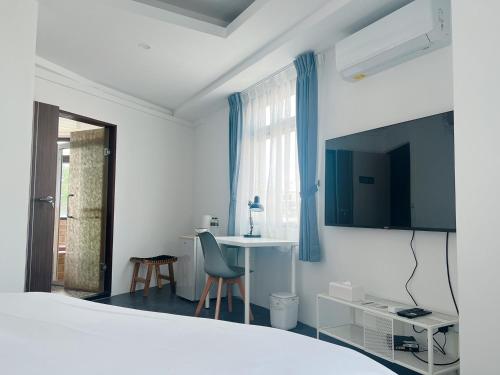 a bedroom with a bed and a table and a tv at 樓梯旅宿-東大門夜市旁-可包棟 in Hualien City