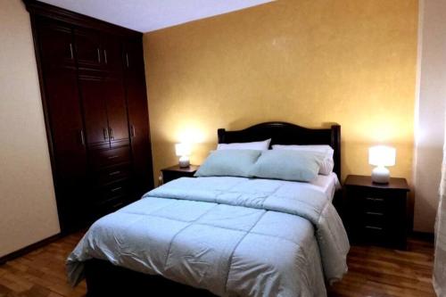 1 dormitorio con 1 cama grande y 2 mesitas de noche en Your Home Away From Home !, en Ambato