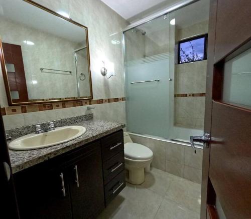 a bathroom with a sink and a toilet and a mirror at Your Home Away From Home ! in Ambato