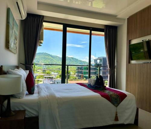 een slaapkamer met een bed en een groot raam bij Apartment with endless mountain view, Pearl 803 in Rawai Beach