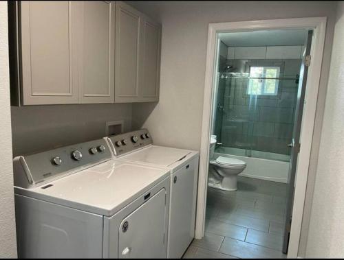 a bathroom with a washing machine and a toilet at New, Fun-Size Benbow House! in Garberville