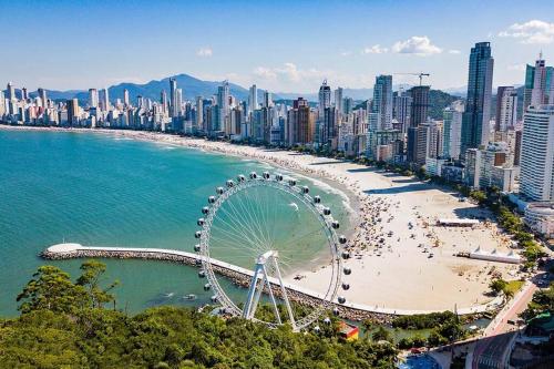 een strand met een reuzenrad en een stad bij Apto à 100m da praia central in Balneário Camboriú