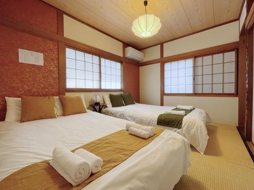 - 2 lits dans une chambre avec fenêtres dans l'établissement North Tengachaya Hotel Apartment, à Osaka