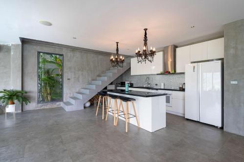 a kitchen with a staircase in the middle of a room at Serenity and Modern Art - Open Hill View 3BR Natural Park Villa 1 in Kamala Beach