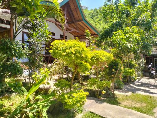 einen Garten vor einem Haus mit Bäumen in der Unterkunft Nadil Homestay in Kuta Lombok