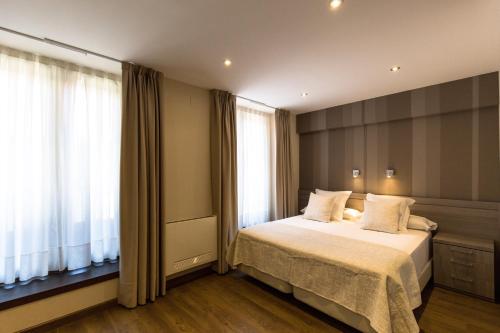 1 dormitorio con cama y ventana grande en Apartamentos Turísticos Llanes en Llanes