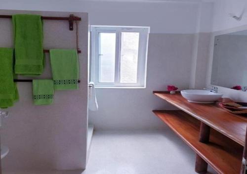 a bathroom with a sink and a window and green towels at Simba House in Watamu