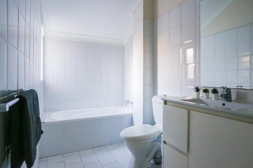a bathroom with a toilet and a tub and a sink at Cozy 2 Bedroom Apartment Chippendale II in Sydney