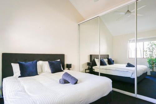 a bedroom with two beds with mirrors and purple pillows at Cozy 2 Bedroom Apartment Chippendale II in Sydney
