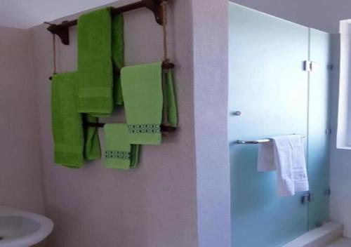 a bathroom with green towels hanging on a wall at Simba House in Watamu