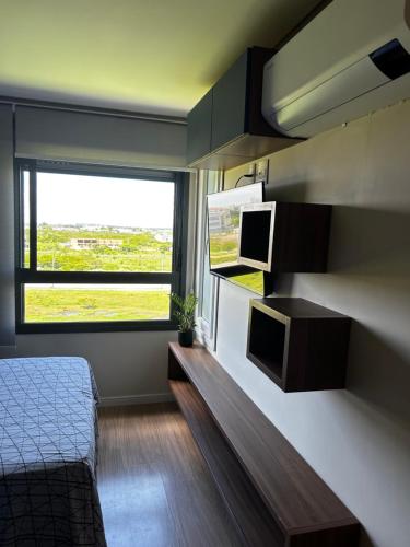 a bedroom with a bed and a large window at Loft Flow Parque Una com garagem! in Pelotas