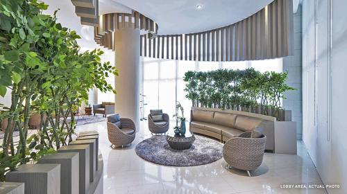 a lobby with a couch and chairs and plants at Grace Residences Elevate Escapes in Manila