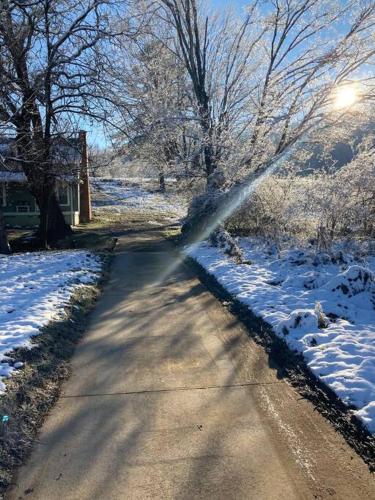 a street with snow on the ground and trees at Farmhouse with game room, fire pit and creek in Johnson City